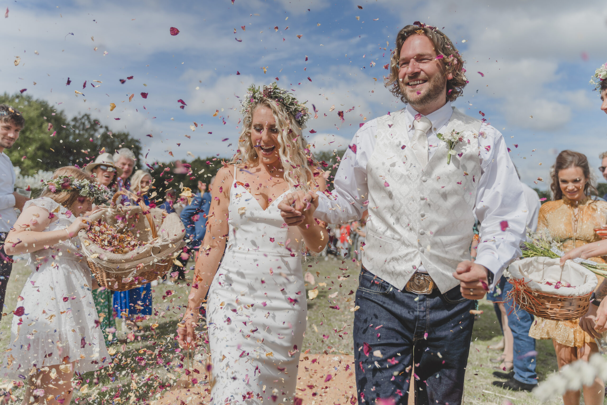 A bride and groom walk down the aisle with confetti thrown at them.