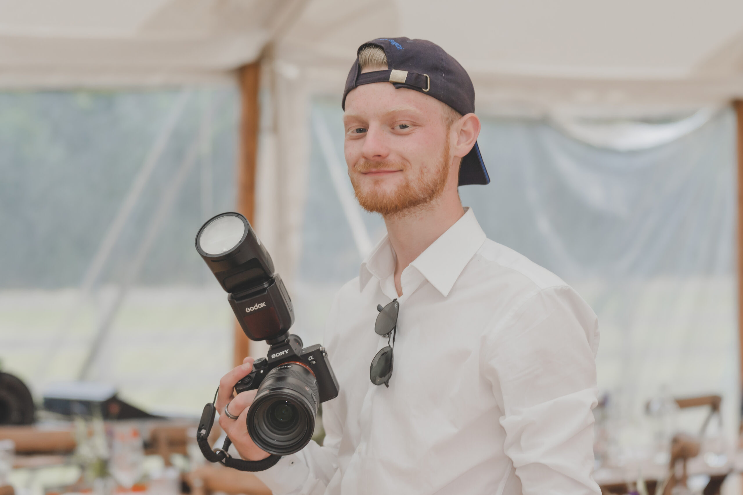 A man holding a camera in front of a tent.